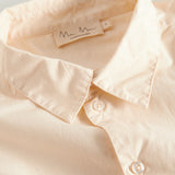 Detaljebillede af krave på cremefarvet bluse