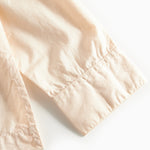 Nærbillede af manchet med knap på cremefarvet bluse