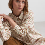 Kvinde iført blomstret skjorte med knaplukning og lange ærmer