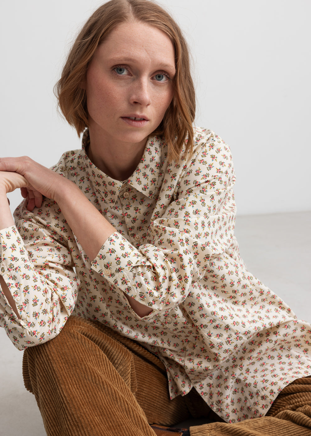 Kvinde iført brune fløjlsbukser og mønstret bluse