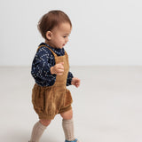 Baby iført brun fløjlsshorts med seler og mørkeblå bluse