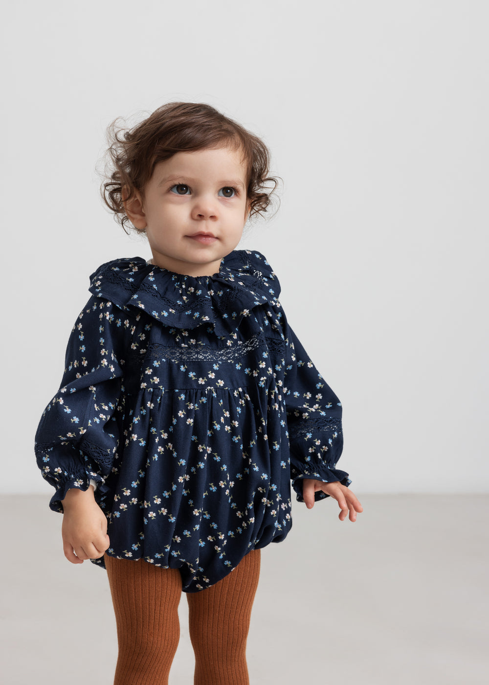 Baby iført mørkeblå blomstermønstret heldragt