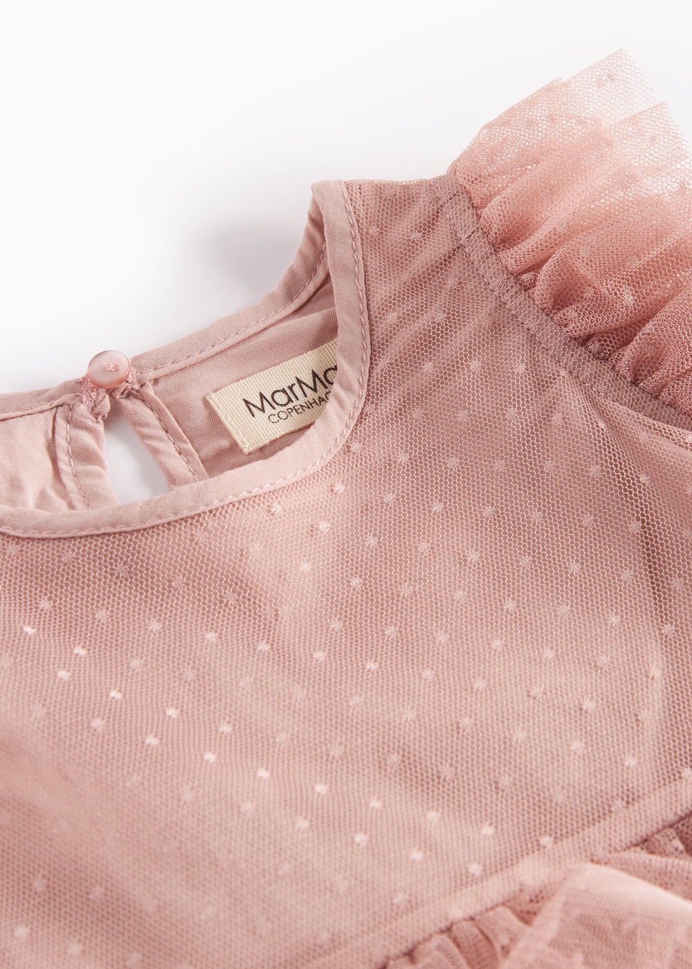 Detaljebillede af lyserød tylkjole med prikmønster og flæser ved halsen