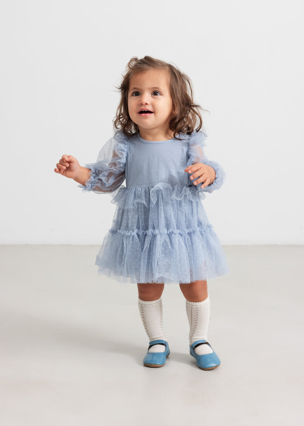 Lille børn i blå tylkjole med flæser og lange ærmer
