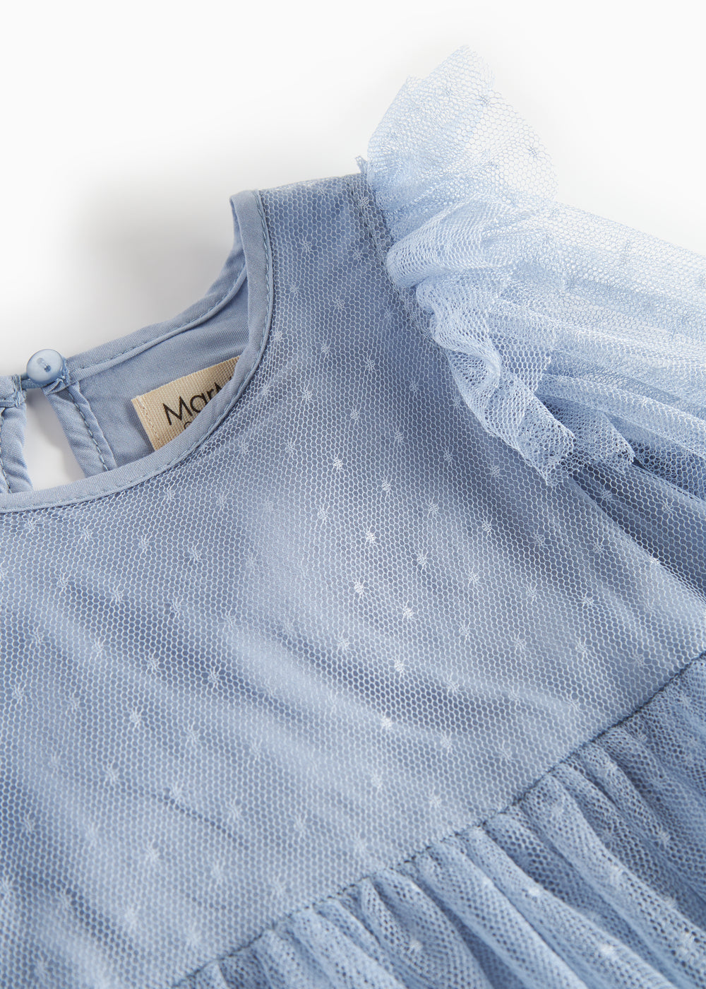 Detaljebillede af blå tylkjole med prikmønster og flæser på skuldrene