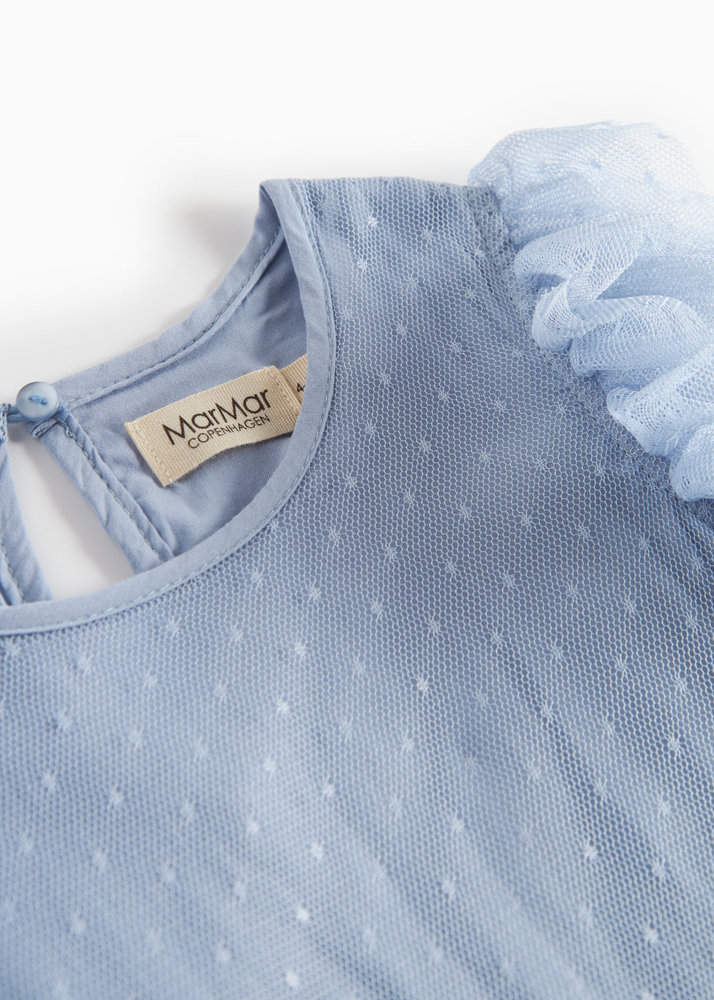 Detaljebillede af blå tylkjole med fint prikmønster og rund hals