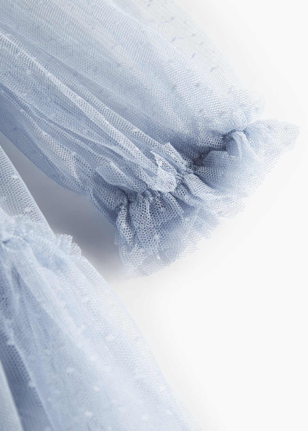 Nærbillede af blå tylkjole med volanger på ærmerne