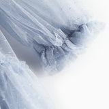 Nærbillede af blå tylkjole med volanger på ærmerne