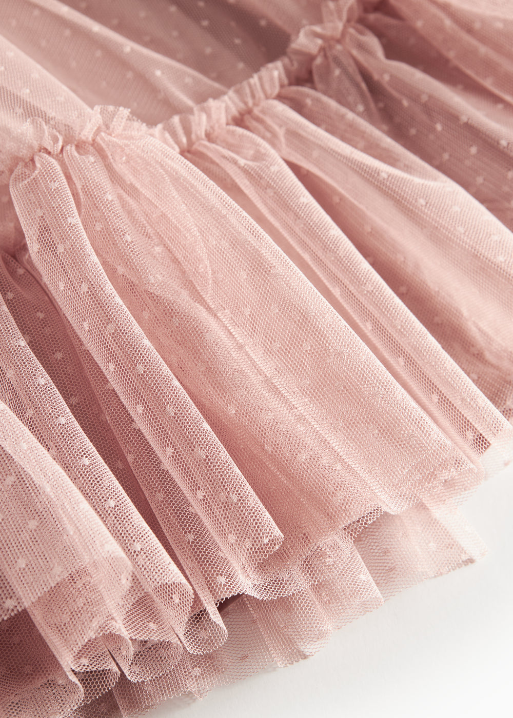 Nærbillede af lagdelt lyserød tylnederdel med fint prikmønster
