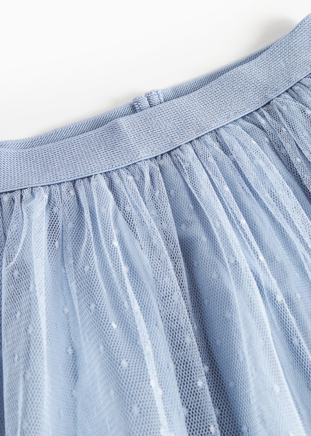 Detaljebillede af blå tylnederdel med prikmønster og elastik i taljen