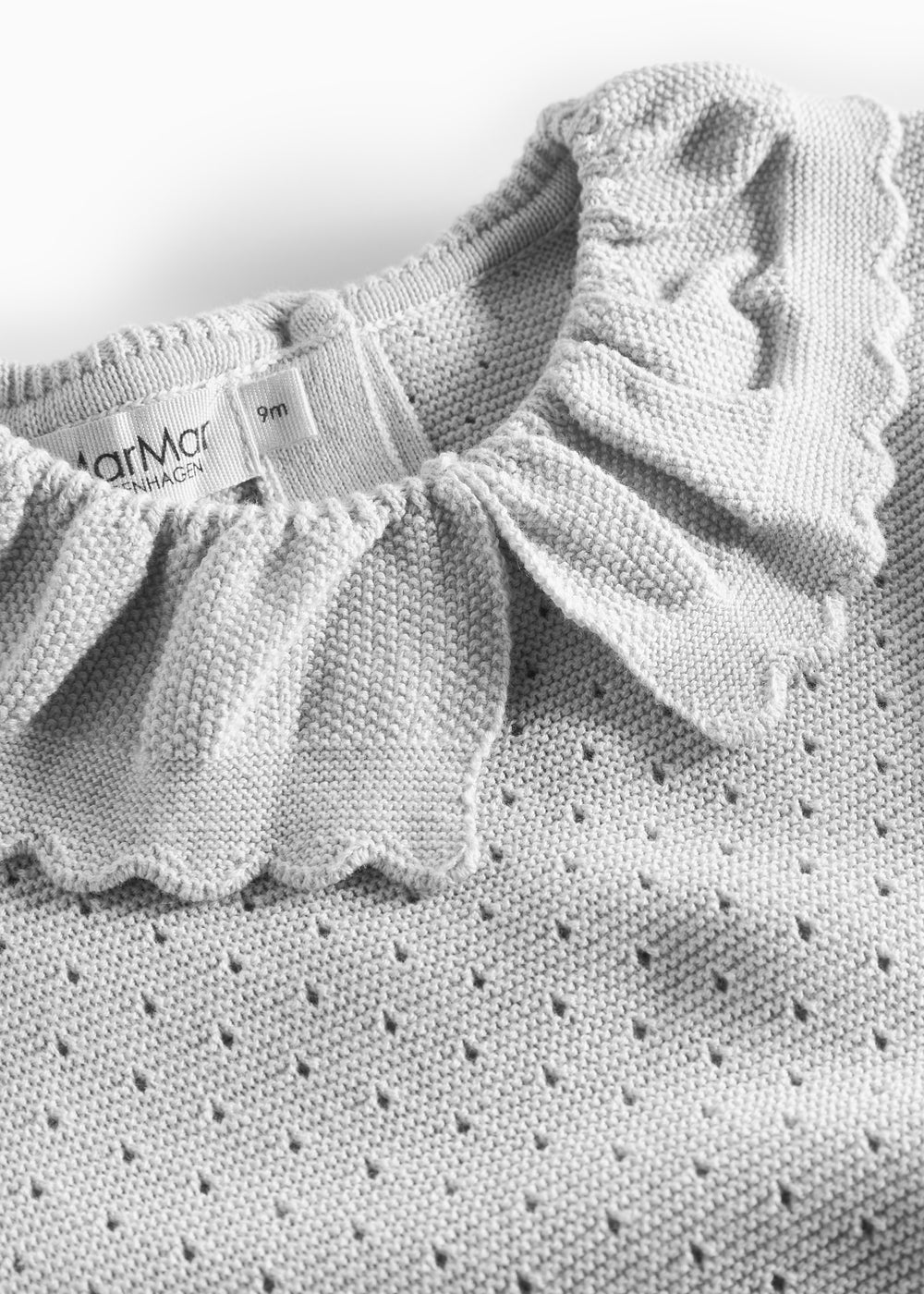 Detalje af flæsekrave på grå strikbluse med hulmønster