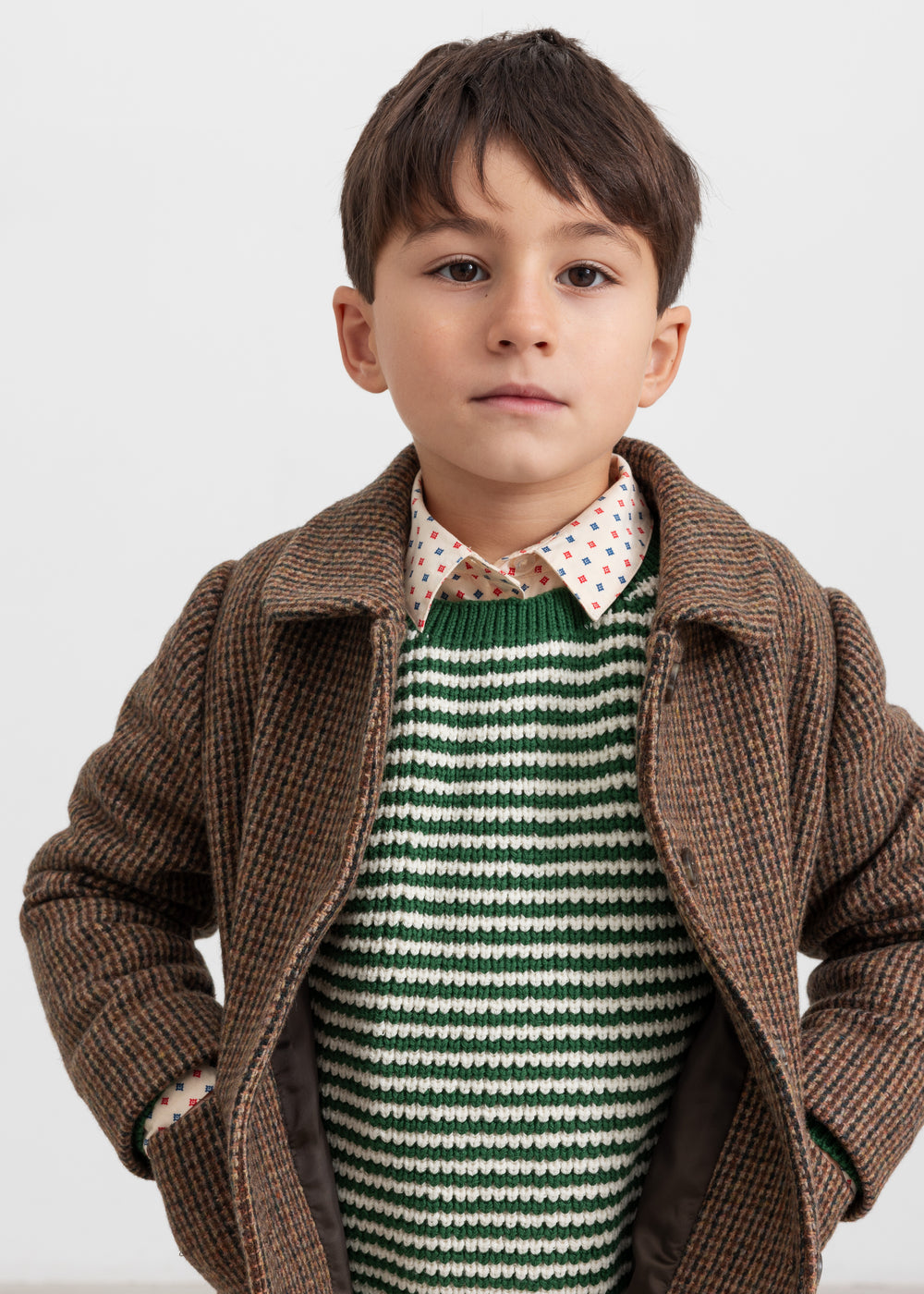 Dreng iført grøn stribet striktrøje med brun jakke