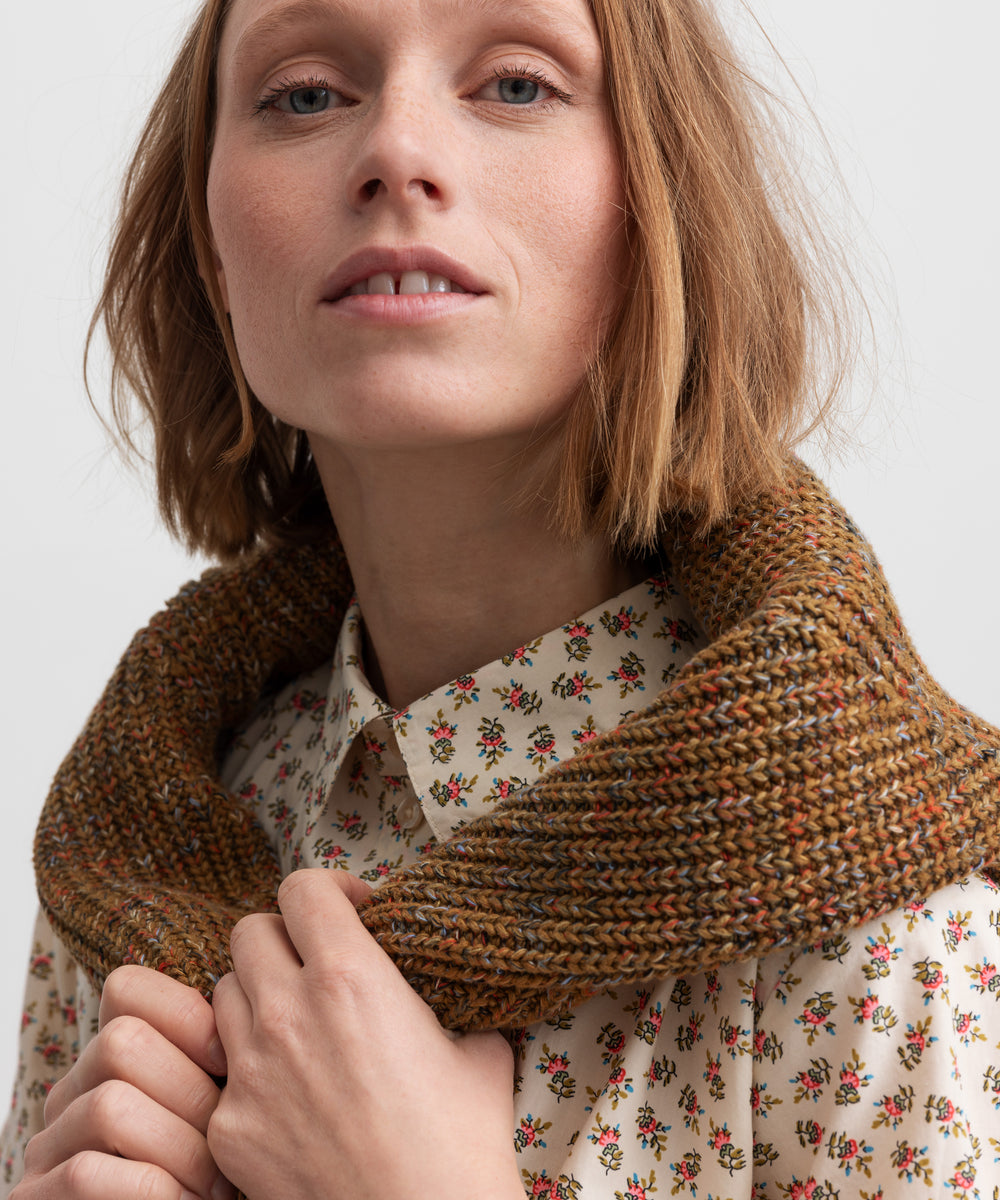 Kvinde iført brunmeleret striktrøje og blomstret skjorte