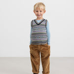 Dreng i brun buks og farverig strikvest med V-hals