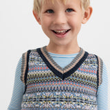 Smilende dreng iført blå og hvid stribet bluse under mønstret strikvest