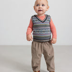 Baby iført beige babyfløjl­sbukser og mønstret strikvest