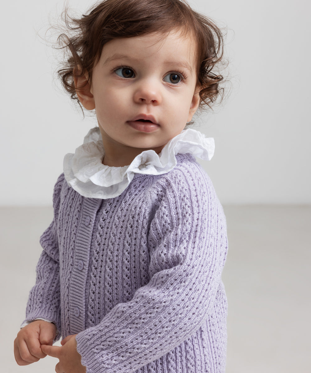 Børn iført lilla strikcardigan med hulmønster og flæsekravebluse