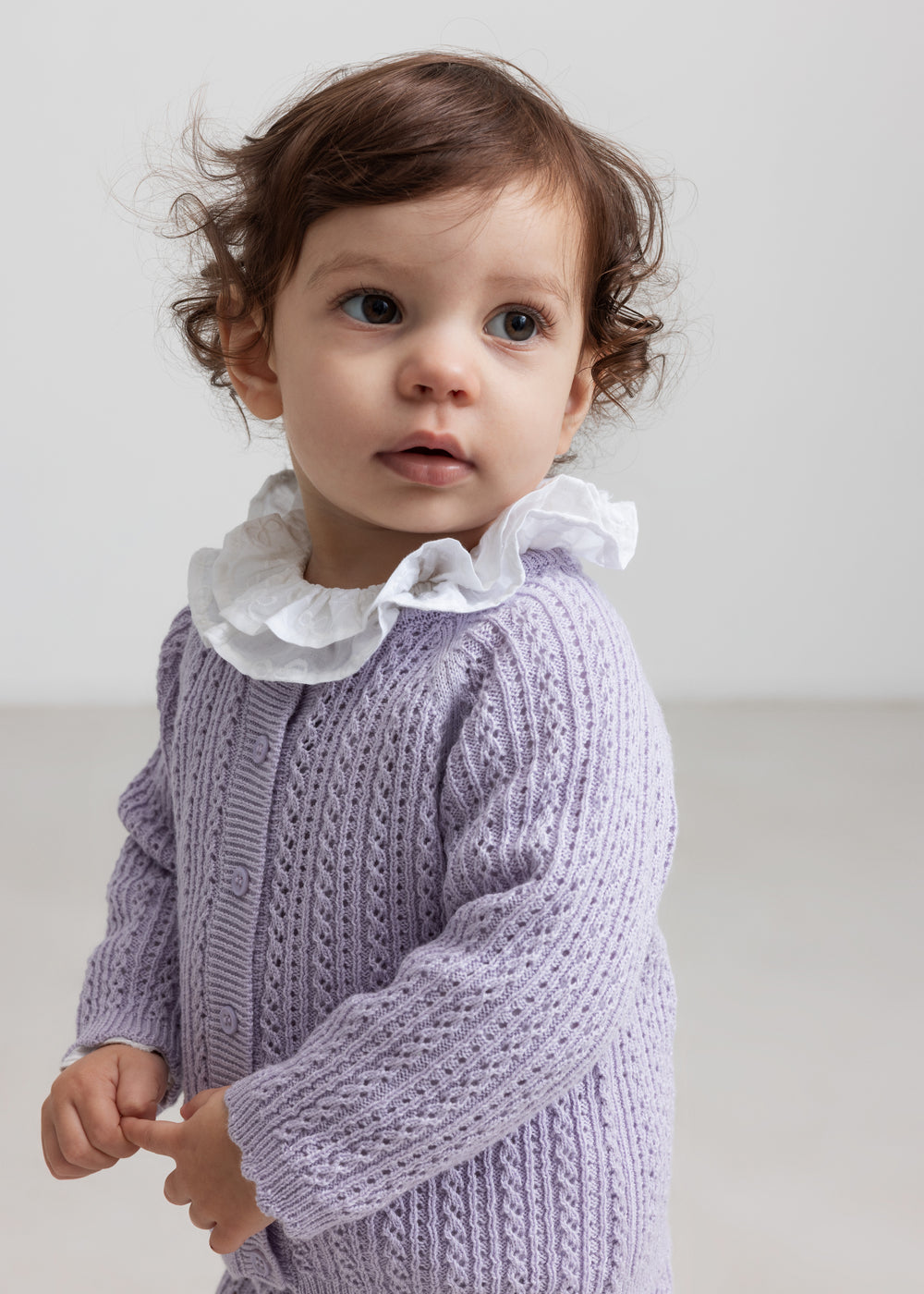 Børn iført lilla strikcardigan med hulmønster og flæsekravebluse