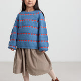 Pige iført beige babyfløjl­s­nederdel og stribet blå bluse