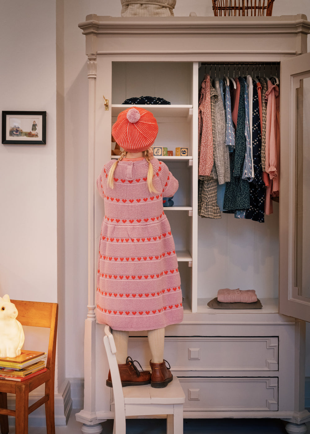 Børn foran garderobe iført rødstribet kjole og matchende beret