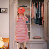 Børn foran garderobe iført rødstribet kjole og matchende beret