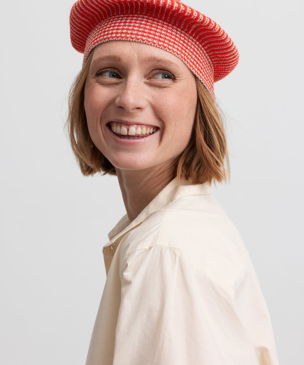 Nærbillede af kvinde med rød hue og cremefarvet bluse