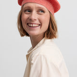 Nærbillede af kvinde med rød hue og cremefarvet bluse