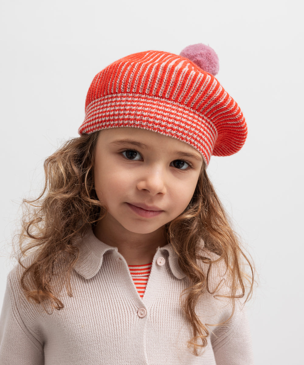 Pige iført rødstribet beret med lyserød kvast