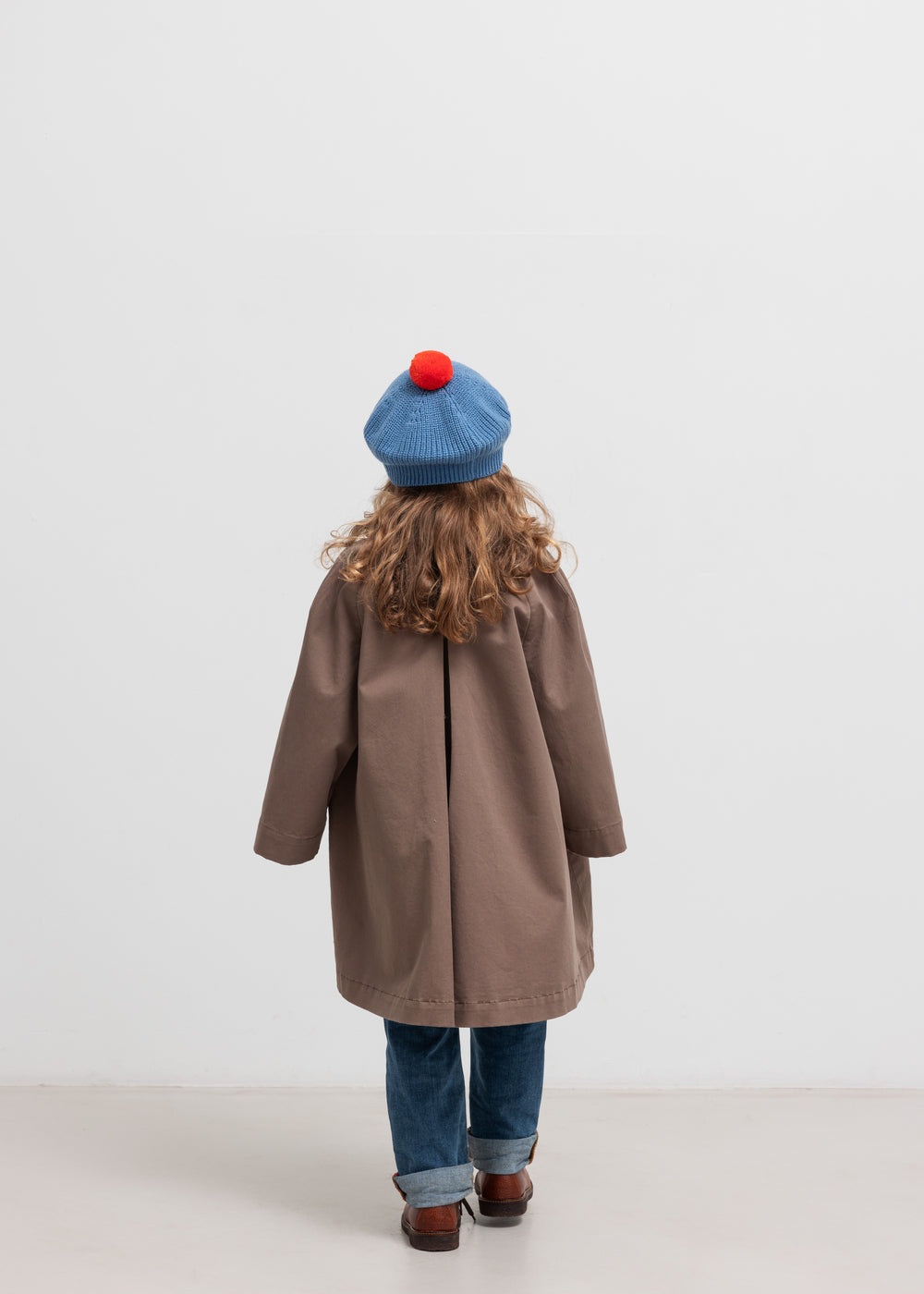 Pige bagfra med blå beret med rød kvast og brun frakke