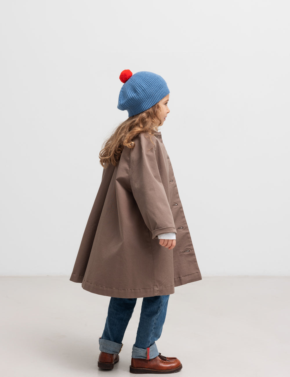 Pige bagfra med blå beret med rød kvast og brun frakke