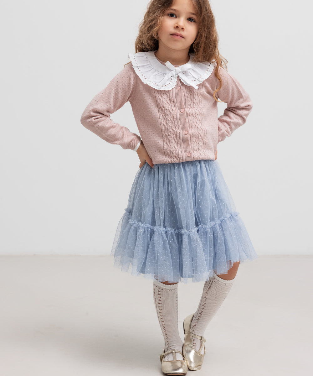 Børn  iført lyserød strikcardigan med blød blå nederdel, stående pose