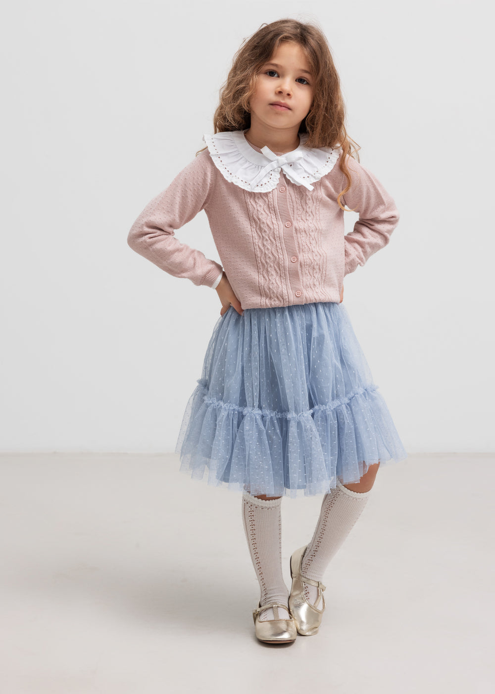 Børn  iført lyserød strikcardigan med blød blå nederdel, stående pose