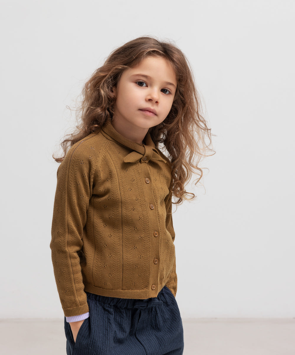 Børn iført brun strikket cardigan og mørkeblå bukser