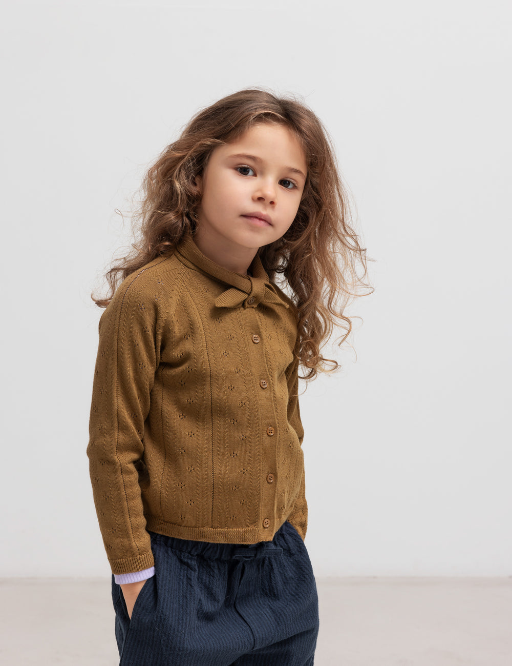 Børn iført brun strikket cardigan og mørkeblå bukser