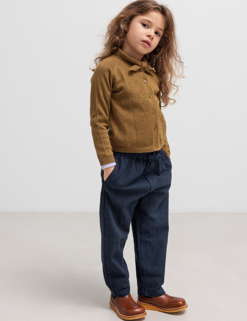 Børn iført brun strikket cardigan og mørkeblå bukser