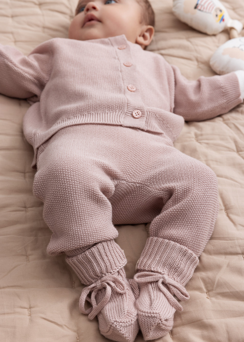 Baby iført lyserød strikket sæt med trøje og bukser