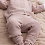 Baby iført lyserød strikket sæt med trøje og bukser