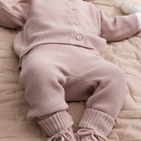 Baby iført lyserød strikket sæt med trøje og bukser