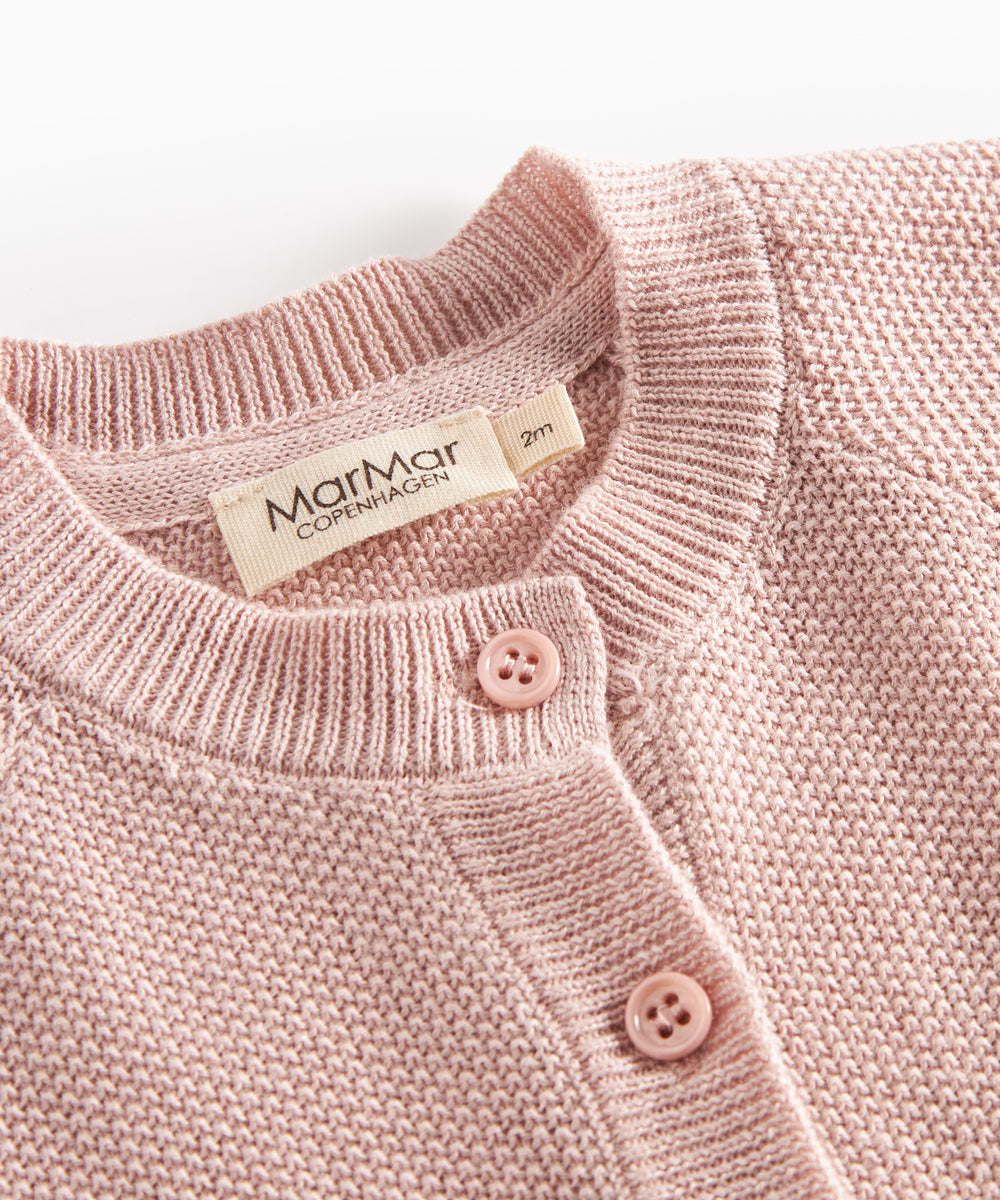 Nærbillede af knapper og halskant på lyserød strikket babycardigan