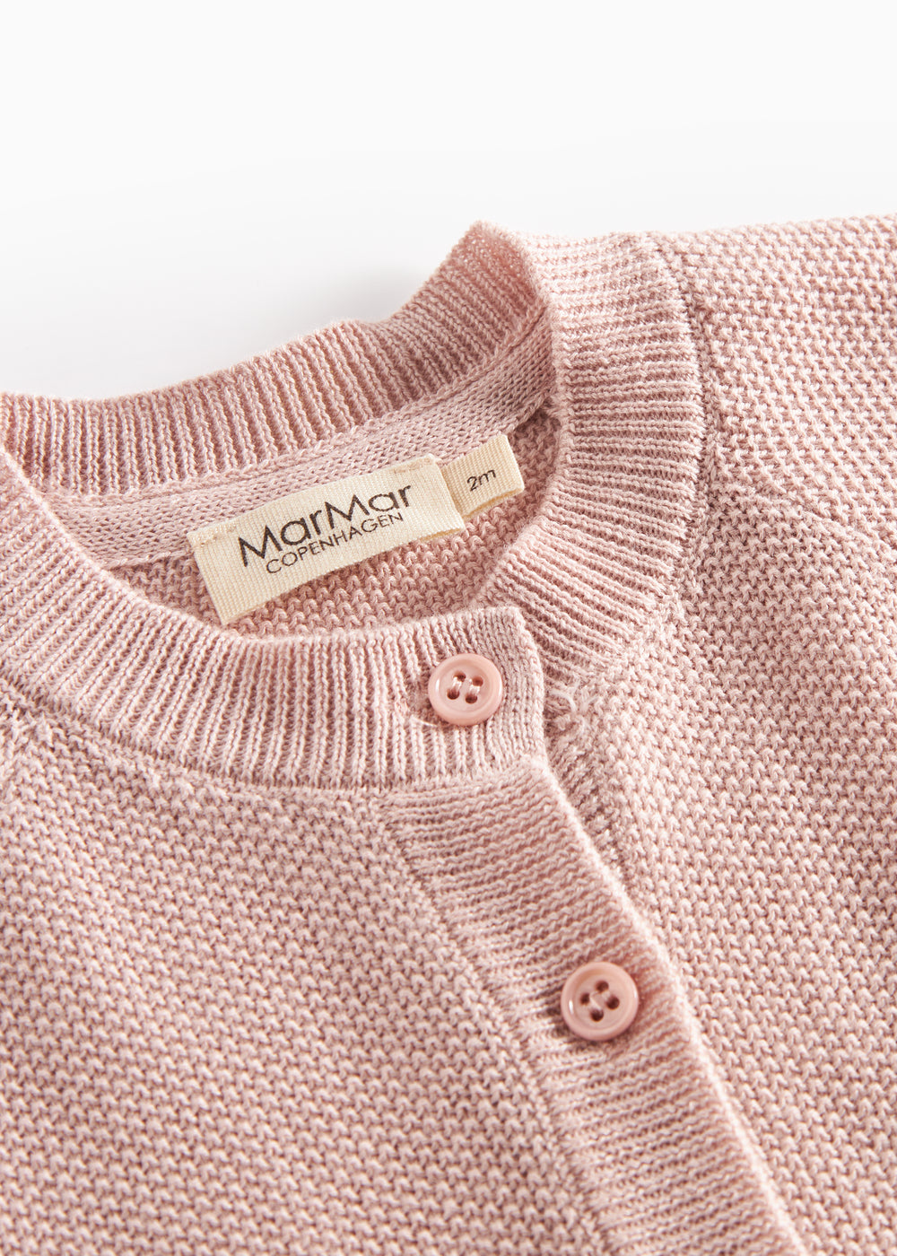 Nærbillede af knapper og halskant på lyserød strikket babycardigan