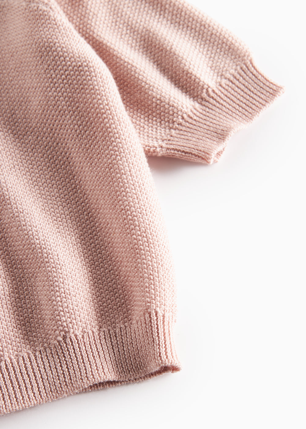 Nærbillede af ribkant ved ærme på lyserød strikket babycardigan