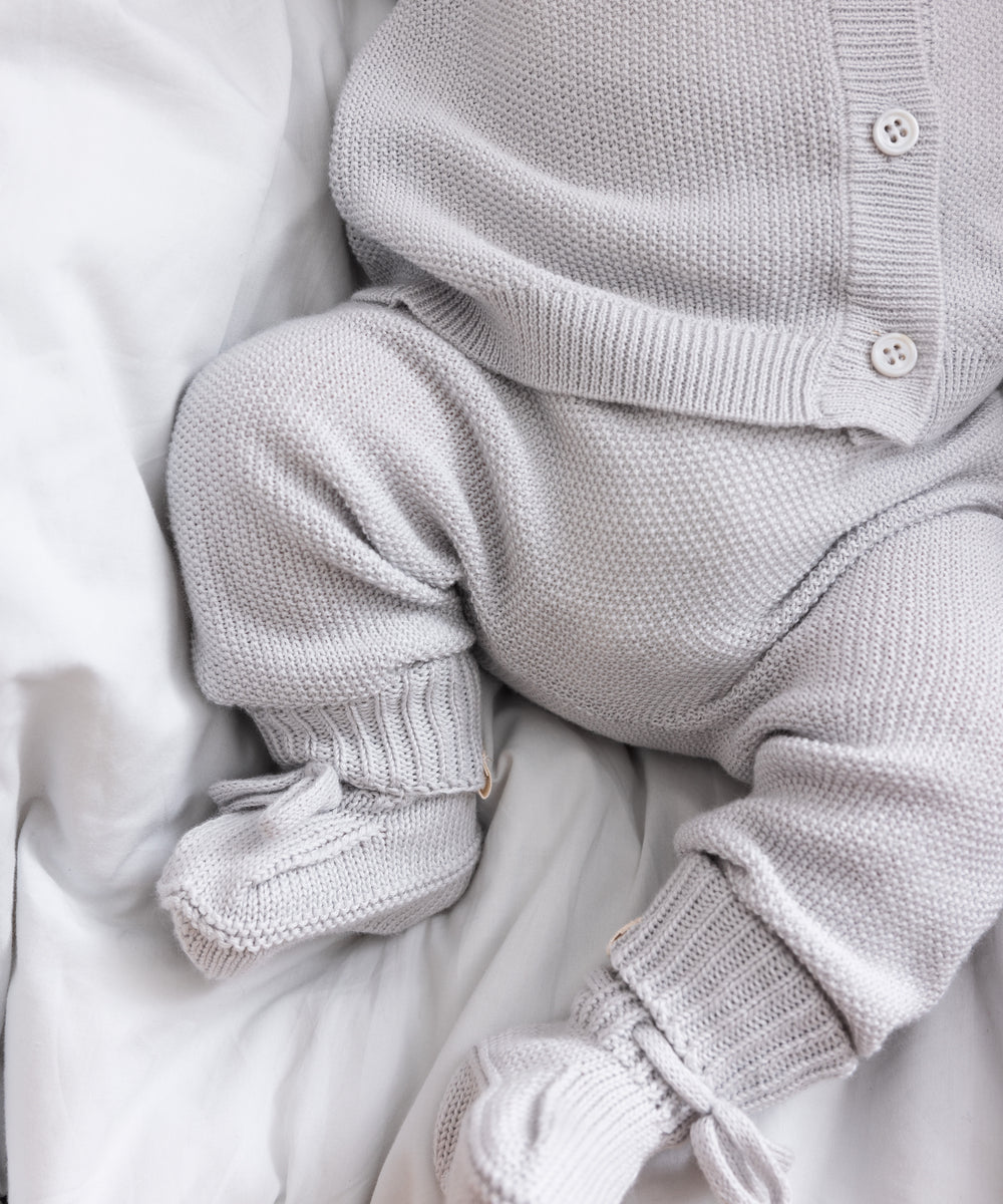 Detalje af babyben i gråt strikket sæt med små strømper