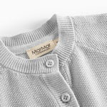 Nærbillede af knapper og halskant på lys grå strikket babytrøje