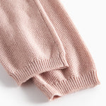 Nærbillede af ribkant på ærme af lyserød strikket babytrøje