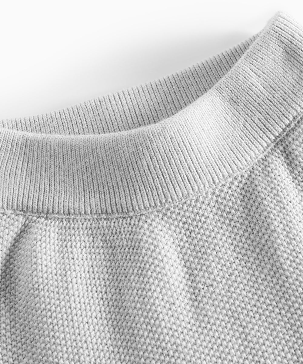 Nærbillede af halsudskæring på grå strikket babytrøje