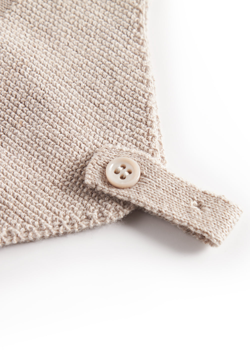 Nærbillede af knaplukning på beige strikket babyhue