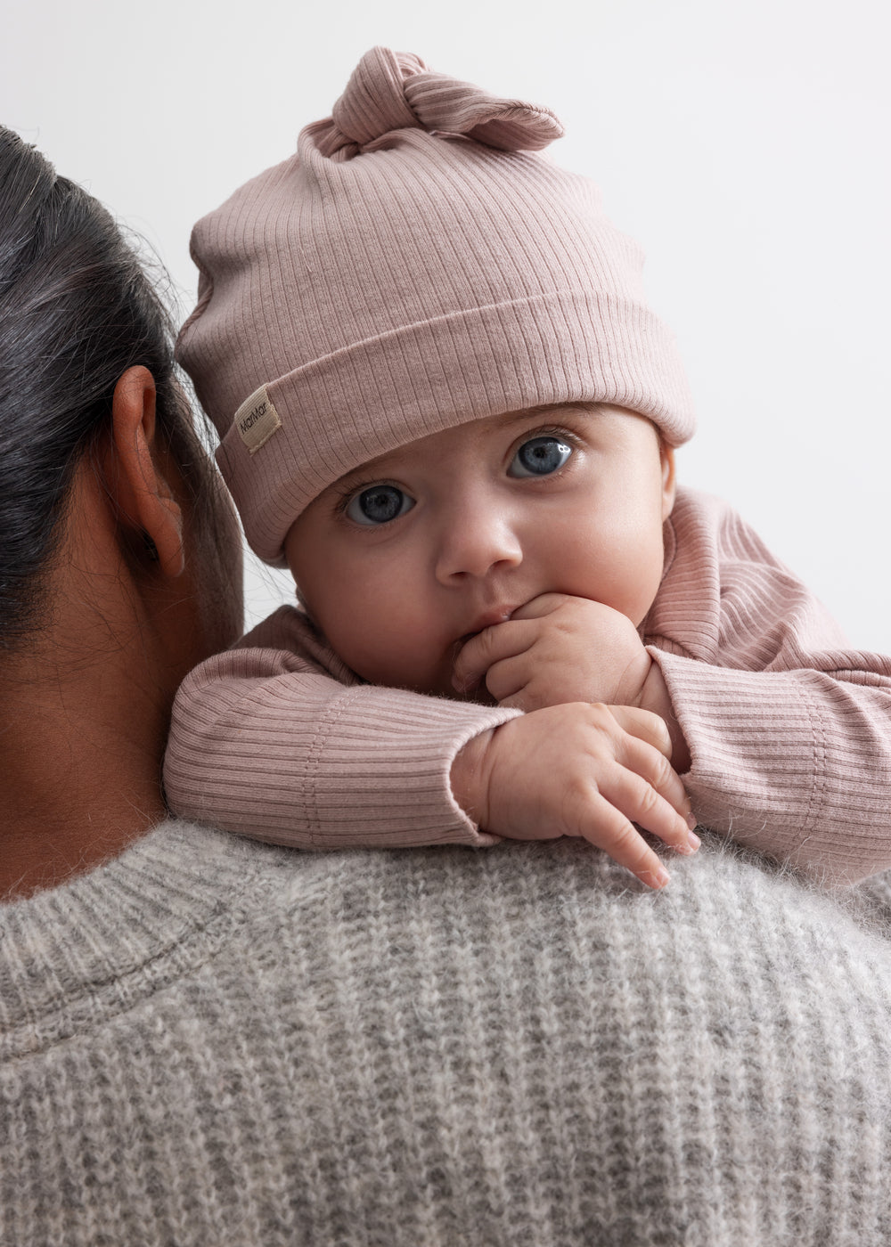 Baby iført lyserød hue og ribstrikket bluse