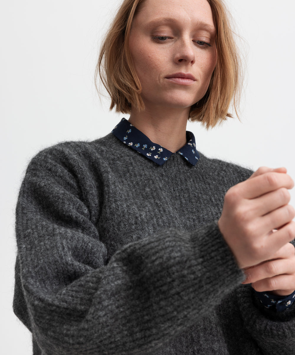 Kvinde iført mørkegrå strikbluse med afslappet pasform