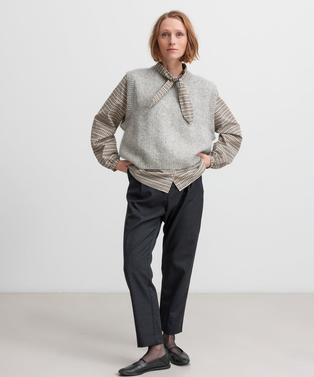 Kvinde iført grå strikvest i uld stylet med skjorte og bukser