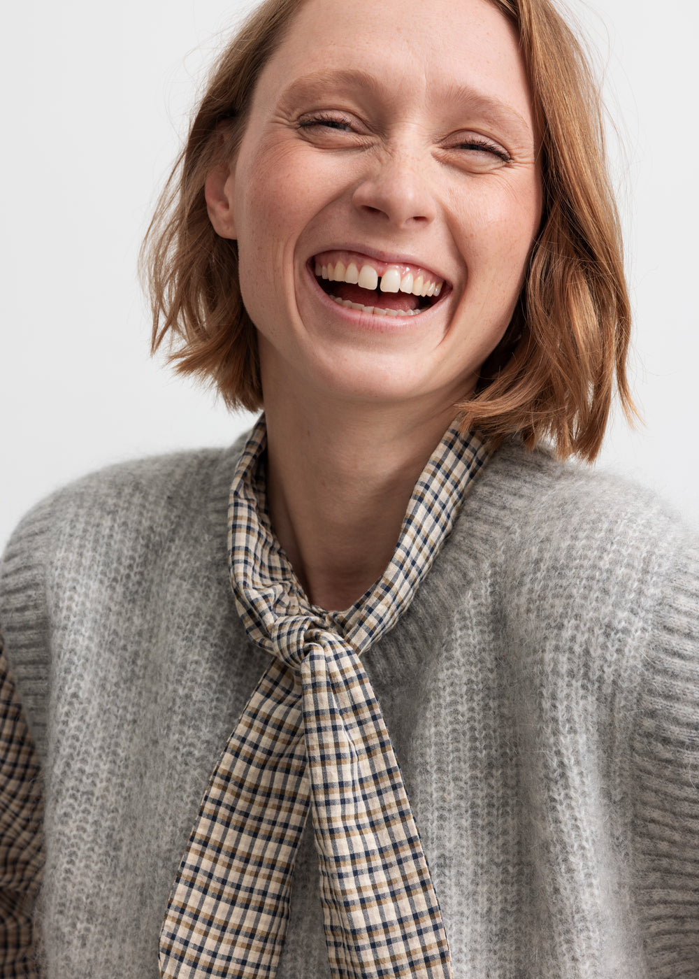 Kvinde iført brun ternet bluse med sløjfe